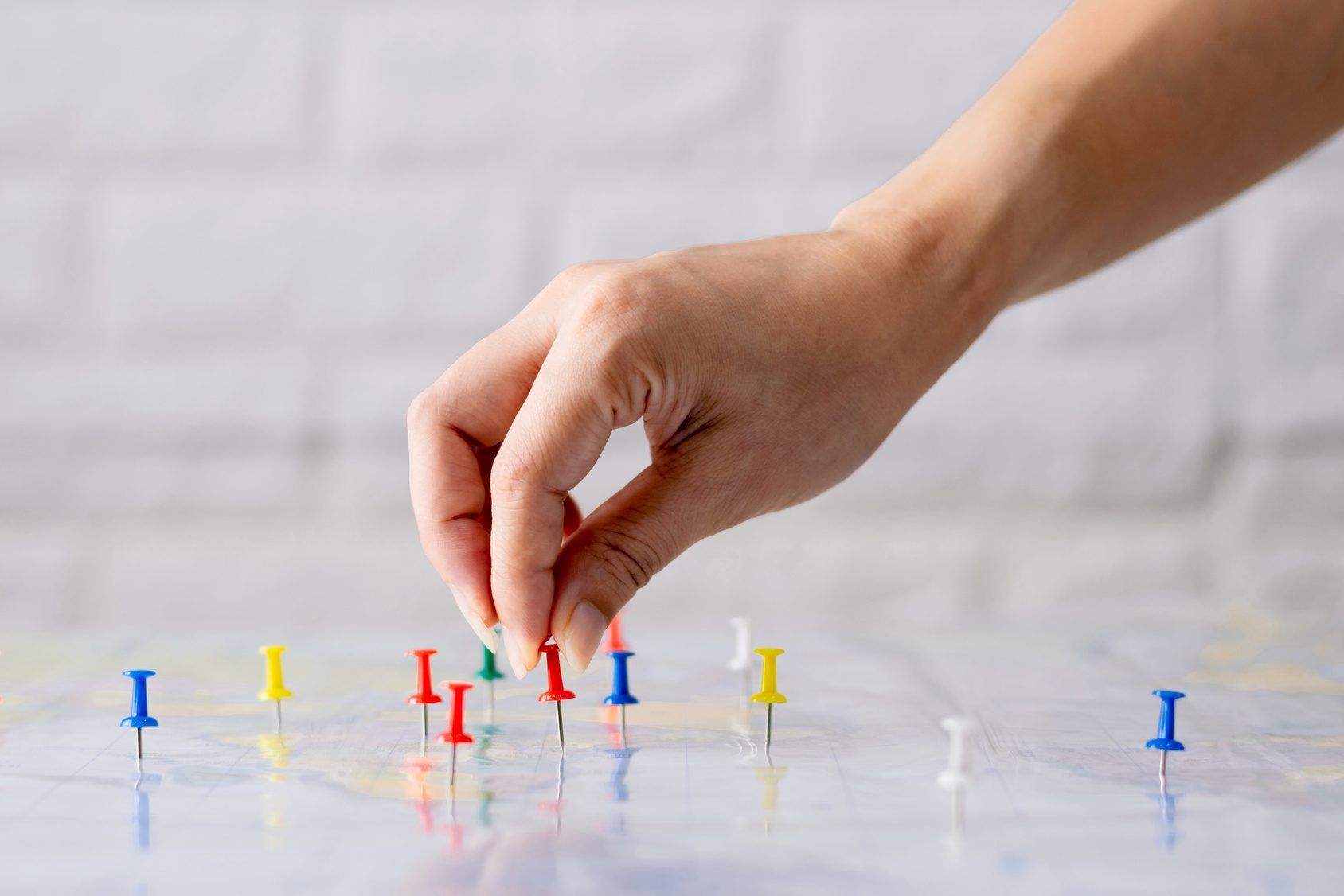 A hand placing pins on a world map