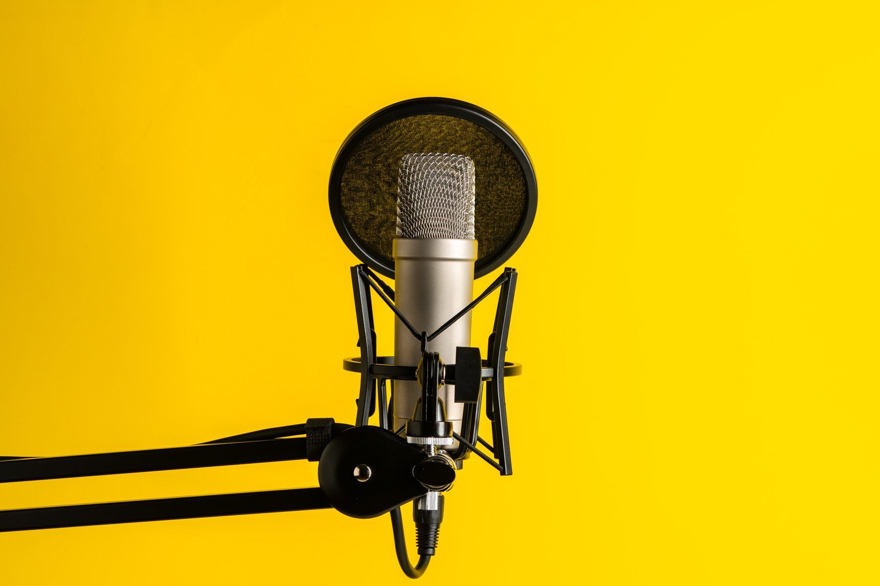 A studio microphone against a bright yellow wall