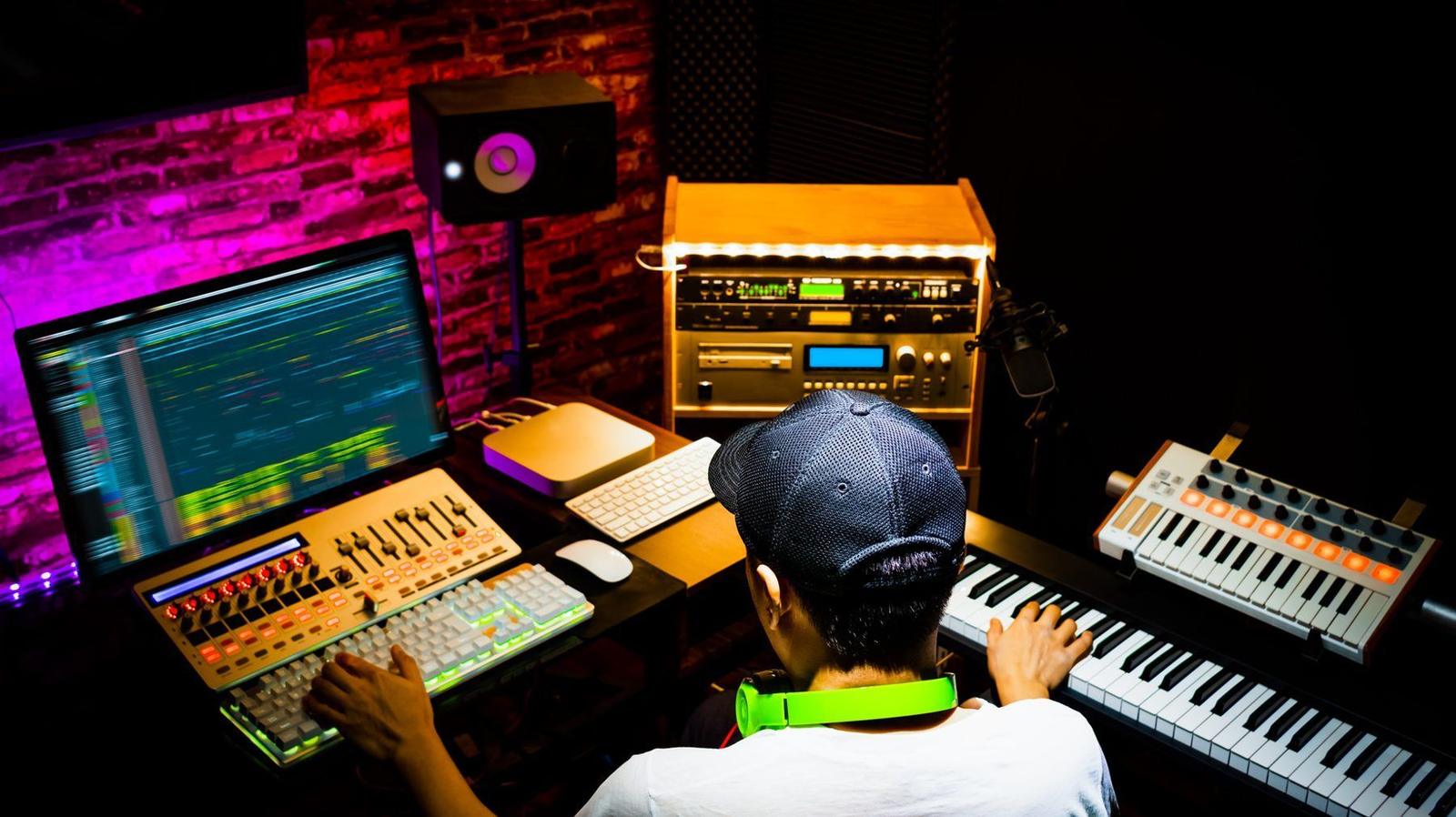 A producer working at a sound design desk with screens and keyboards