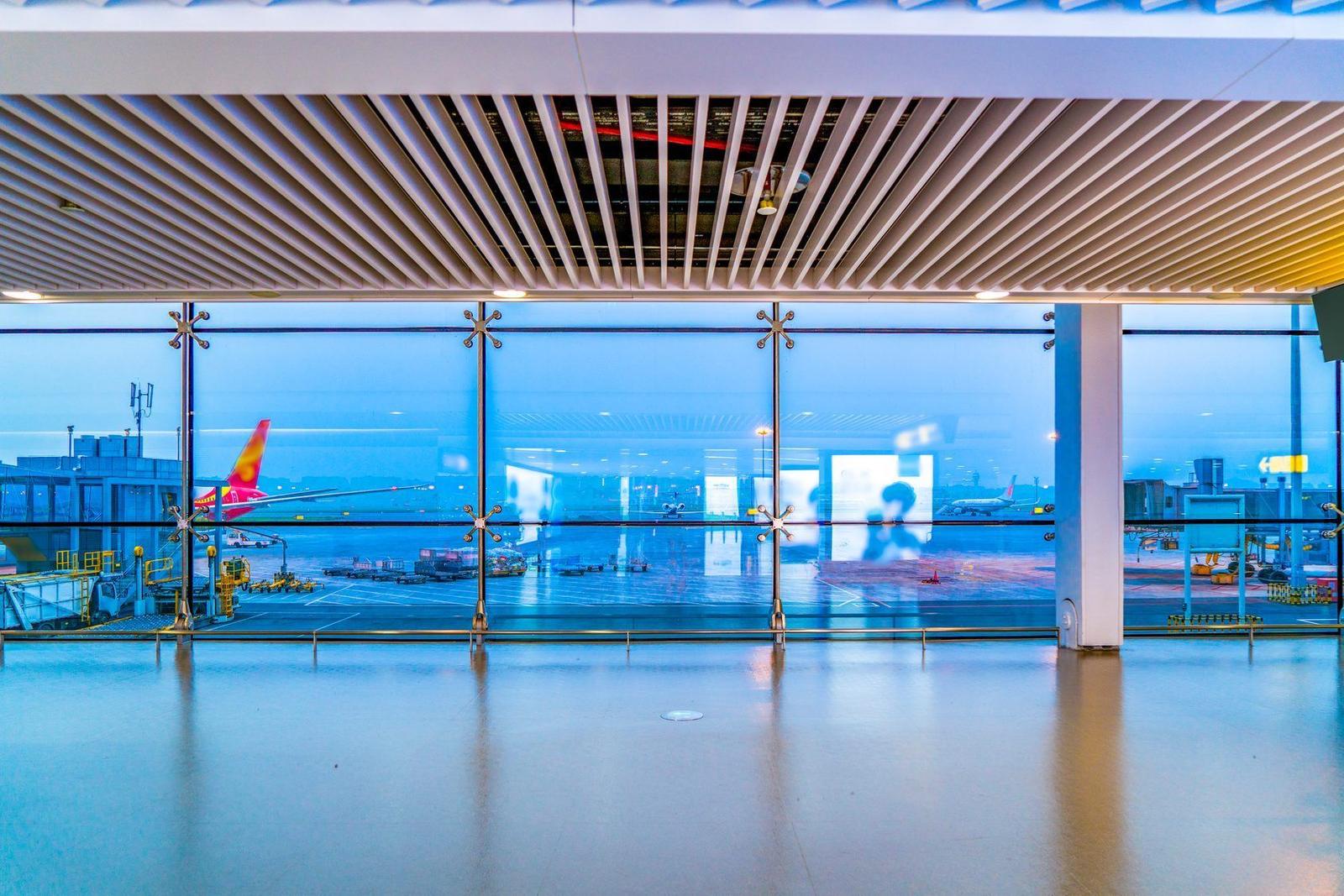 A bright, empty airport departure hall with runway views