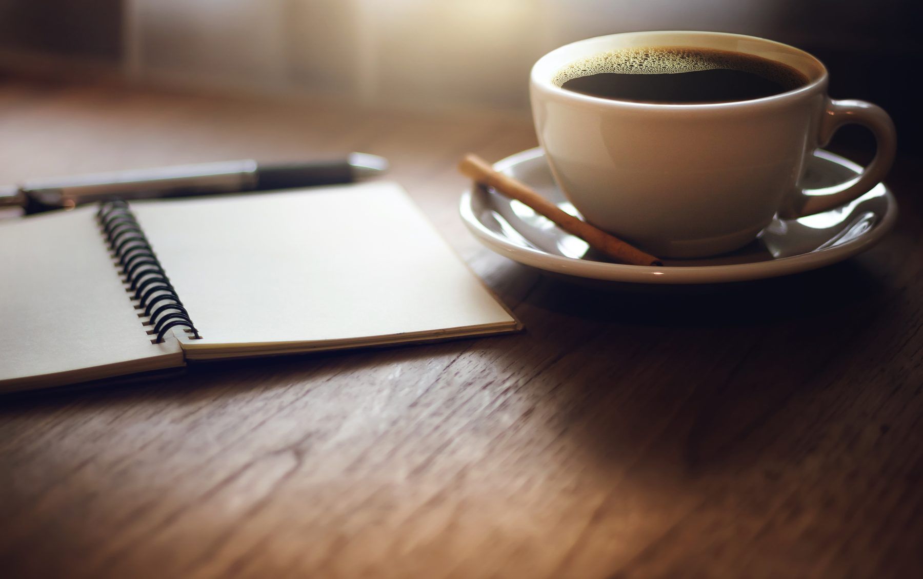 An open notebook beside a cup of coffee