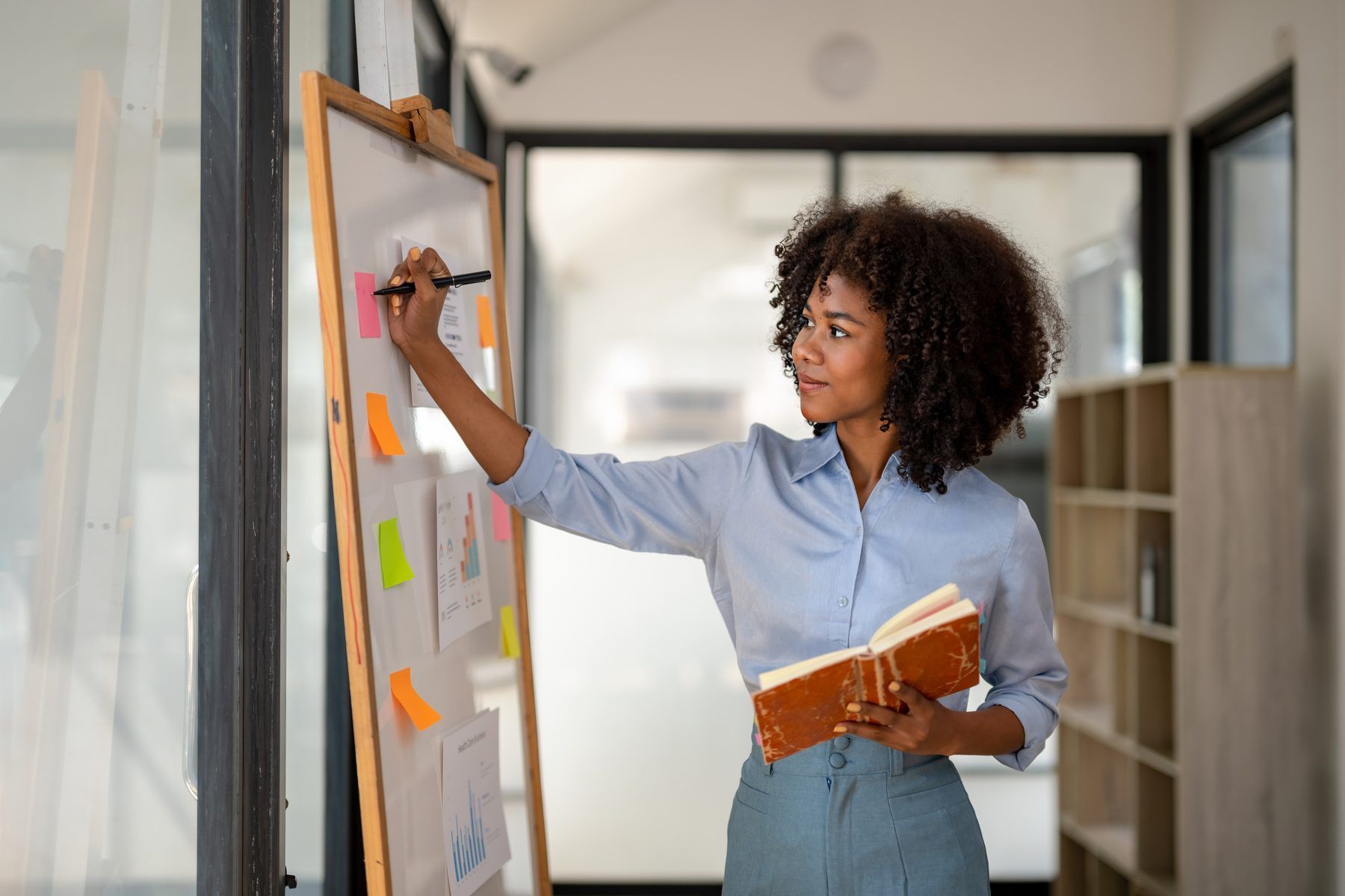 A woman mapping out a plan on a wall of sticky notes