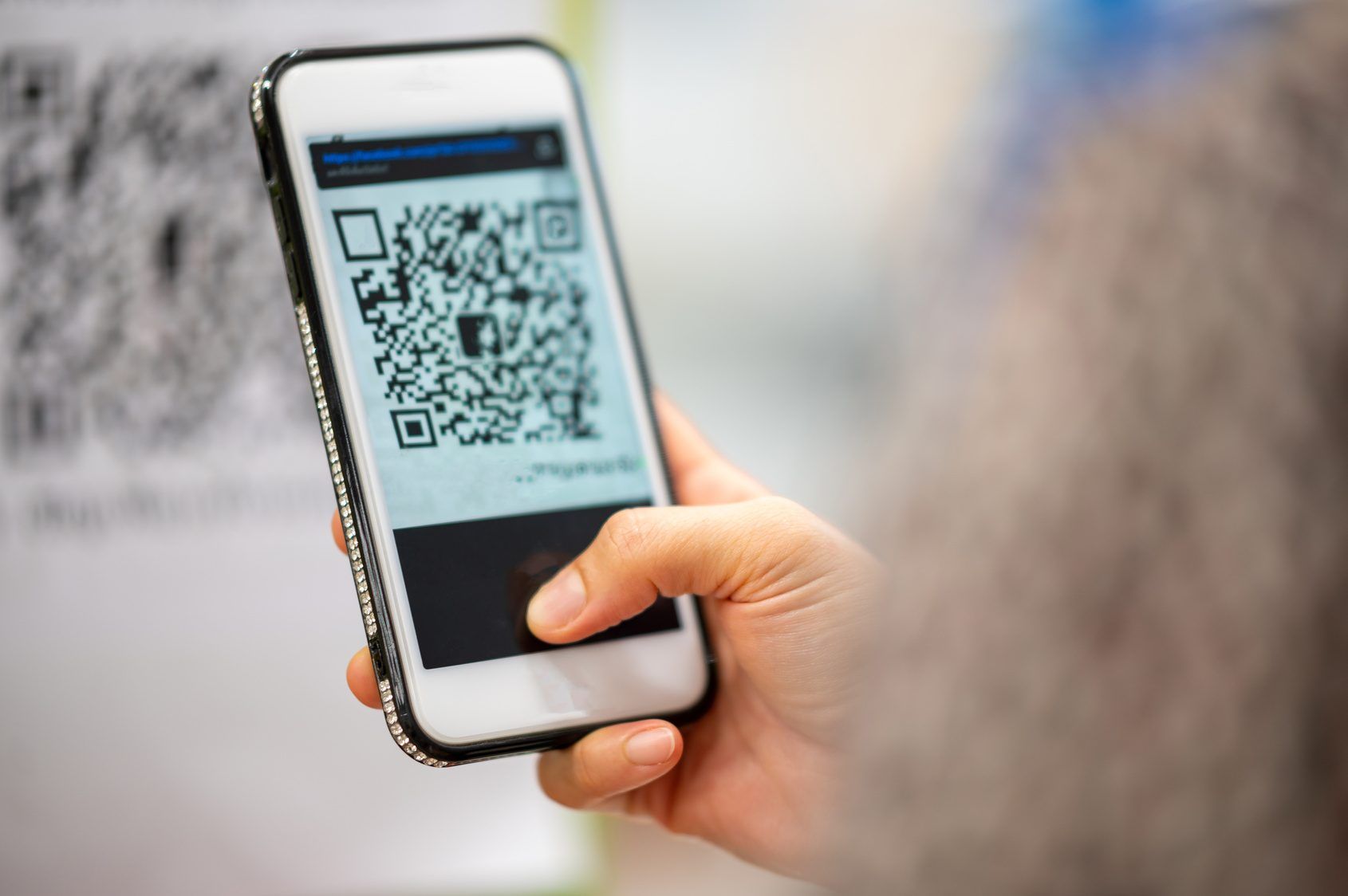 A hand holding a smartphone to scan a payment code