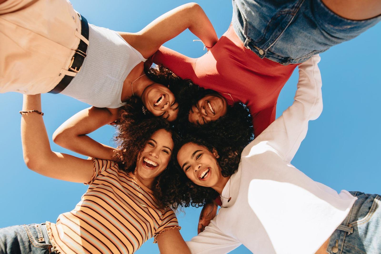 Four smiling women in a circle, looking down at the camera